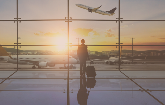 Business traveler with suitcase at airport window watching sunrise and airplane take off – symbolizing jet lag, travel fatigue, and circadian rhythm reset.